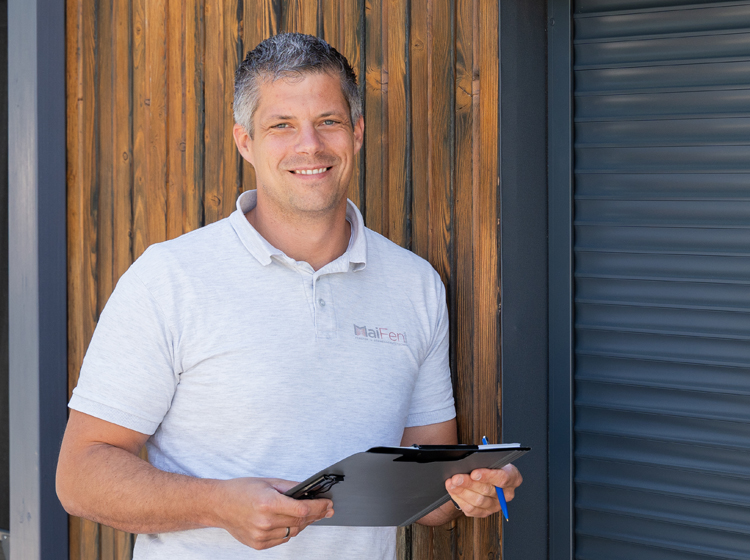 Über-Uns-MaiFen-GmbH-Ing.Maislinger-Beratung Portrait von Ing. Maislinger Geschäftsführer von MaiFen GmbH mit einem Tablet in der Hand neben einem Solar-Rollladen