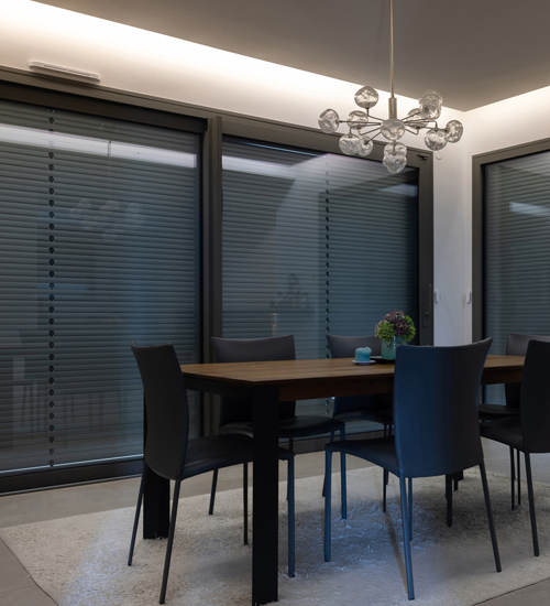 Solar-Rollladen 5 Wohnzimmer mit Esstisch mit großer Fensterfront, die mit Solar-Rollladen mit geschlossenen jalousierbaren Lamellen vor der Sonne geschützt ist