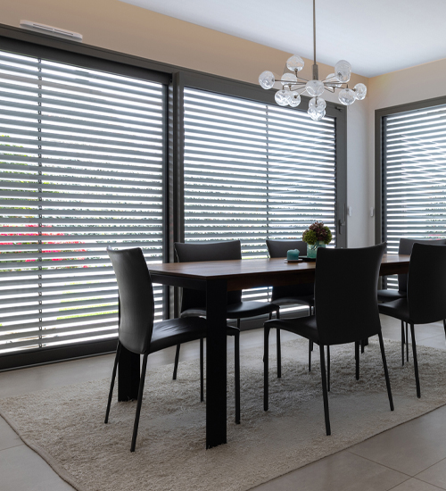 Solar-Rollladen 4 Wohnzimmer mit Esstisch mit großer Fensterfront, die mit Solar-Rollladen mit geöffneten jalousierbaren Lamellen vor der Sonne geschützt ist